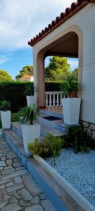 uma casa com um pátio com vasos de plantas em Villa Rosa de los Vientos em Les tres Cales