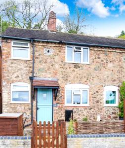 a brick house with a blue door and a fence at Romantic & Cosy Cottage with Direct Access to the Hills in Malvern Wells