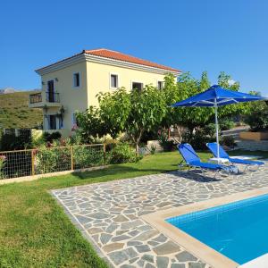 een huis met een zwembad en twee stoelen en een parasol bij Villa Farangi in Gállos