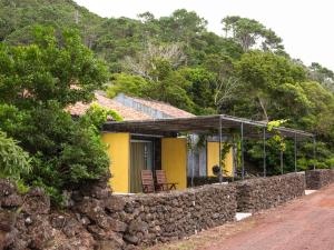 a yellow house with a stone wall at Casas do Amarelo in São Mateus