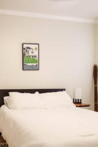 Un dormitorio con una cama blanca con una foto en la pared en Gateway Retreat: Short Drive to the Sequoias, en Exeter