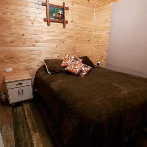 1 dormitorio con 1 cama y pared de madera en Cabañas El Roble, en Dalcahue