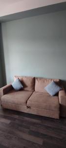 a brown couch sitting in a living room with two pillows at Sunny apartment in Kechi House, Tsaghkadzor in Tsaghkadzor