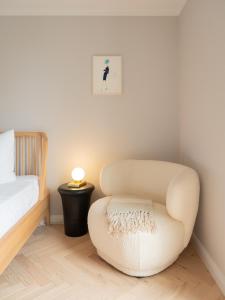 ein Schlafzimmer mit einem weißen Stuhl und einem Bett in der Unterkunft Das Sellin - Auszeit mit eigenem Seezugang und Sonnengarten in Heringsdorf