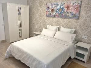 - une chambre avec un lit blanc et une peinture murale dans l'établissement Apartamentos Guadalupe Gran Canaria Puerto Rico, à Mogán