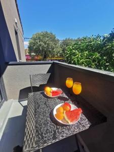 una mesa con platos de fruta y vasos en el balcón en Oasis in the city near Amfiteatar,free parking and free Wi-Fi, en Pula