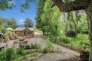 a cabin in the woods with a fence and trees at The Loveshack Lodge Balquhidder in Balquhidder