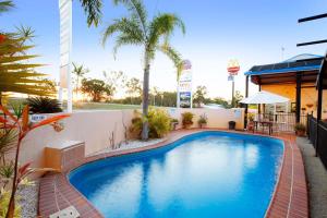 a swimming pool in a resort with palm trees at Glenmore Tavern in Rockhampton