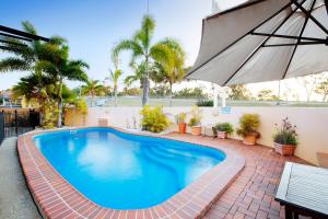 a swimming pool with an umbrella and palm trees at Glenmore Tavern in Rockhampton