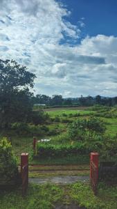 un campo con una valla y un campo con árboles en Chilly Coorg en Virajpet