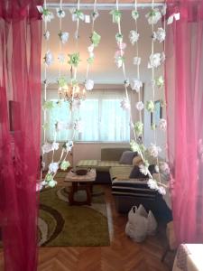 a living room with pink curtains and white flowers at Stan na dan Novi Grad in Bosanski Novi