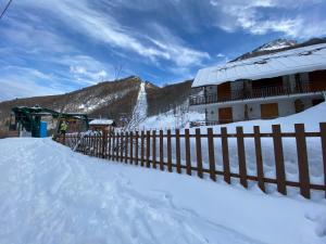 a building with a fence in the snow at La Baita Limone Riserva Bianca Ski-in Ski-out Seggiovia Morel 1 in Limone Piemonte