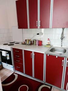 una cocina con armarios rojos y fregadero en Stan na dan Novi Grad, en Bosanski Novi