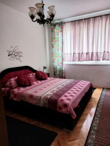 Un dormitorio con una cama con almohadas rojas y una ventana en Stan na dan Novi Grad, en Bosanski Novi