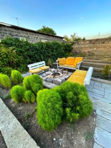 een tuin met twee banken en een vuurplaats met groene planten bij Unoyan Guest House in Gjoemri