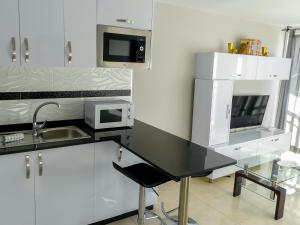 cocina con armarios blancos y encimera negra en Apartamentos Guadalupe Gran Canaria Puerto Rico, en Mogán