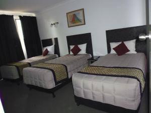 um quarto de hotel com três camas num quarto em Burke & Wills Motor Inn em Kingaroy