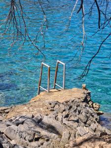 un banc assis au sommet d'une roche près de l'eau dans l'établissement Cottage made of stones and wood with the sea view., à Blato