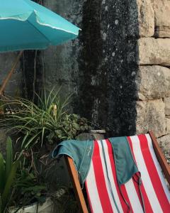 a towel on a chair next to an umbrella at Cottage made of stones and wood with the sea view. in Blato