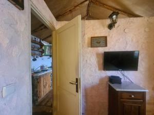 a room with a television on the wall and a kitchen at Cottage made of stones and wood with the sea view. in Blato