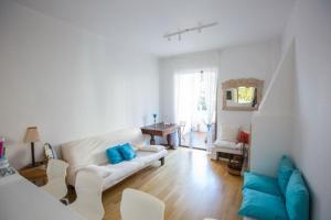 a living room with a white couch and blue pillows at Άνετη διαμονή 100 μέτρα από τη θάλασσα - Βάρκιζα in Vari