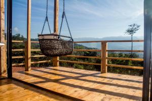 un porche con una cesta colgante en una terraza de madera en Casa el Ocobo, proyecto ecodependiente, en Silvania