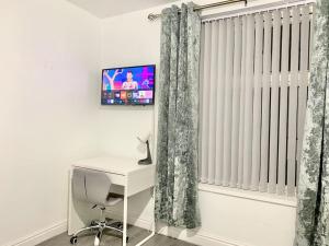 a room with a desk and a window with a tv at Kunda House Sparkbrook in Birmingham