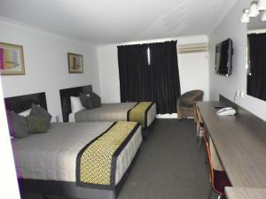 a hotel room with two beds and a desk at Burke & Wills Motor Inn in Kingaroy