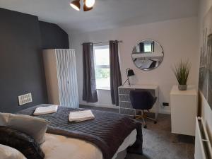 een slaapkamer met een bed, een spiegel en een bureau bij 93 Newtown Road in Great Malvern