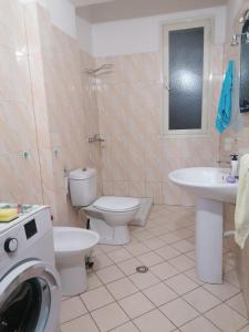 ein Badezimmer mit Toilette, Waschbecken und Waschmaschine in der Unterkunft Appartamento incantevole con posto auto privato in Vlorë