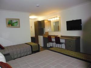 una camera d'albergo con un letto e una scrivania con una televisione di Burke & Wills Motor Inn a Kingaroy