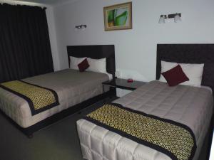 two beds in a room with two lamps at Burke & Wills Motor Inn in Kingaroy