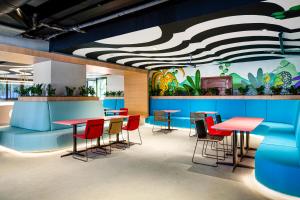 a restaurant with red tables and chairs and a painting on the wall at JO&JOE Rio de Janeiro Largo do Boticario in Rio de Janeiro