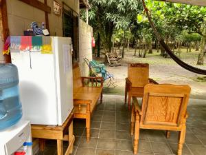 a room with benches and a refrigerator and a table and chairs at Nanda Parbat Hostal in San Rafael Cedros