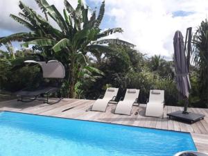 a pool with two lounge chairs next to a swimming pool at Villa Kajou in Sainte-Anne