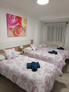 two beds in a room with pink and white sheets at apartamento Miñes in Zaragoza