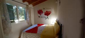 a bedroom with a bed and a window with red flowers on the wall at Il Rifugio Di Artemide AGRITURISMO in Perinaldo