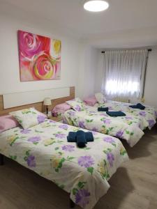2 camas en una habitación de color púrpura y rosa en apartamento Miñes en Zaragoza
