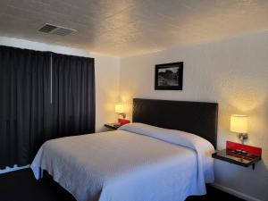 a bedroom with a large white bed with two lamps at Rocket Motel in Custer