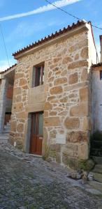 un edificio de piedra con una puerta marrón en Casa Cereja, en Pêro Viseu