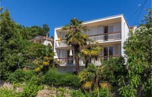 a white building with palm trees in front of it at 2 Bedroom Awesome Apartment In Icici in Ičići