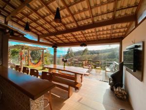 a dining room with a table and chairs and a large window at Casa de Campo no Caravaggio ao lado da Cervejaria Três Santas in Santa Teresa