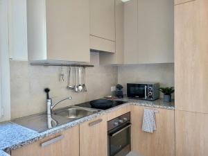 a kitchen with a sink and a microwave at Apartment PALMA - Central & Cozy with Free Private Parking in Lugano