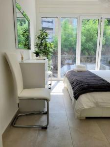 a bedroom with a bed and a chair and windows at Apartment PALMA - Central & Cozy with Free Private Parking in Lugano