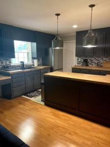 a large kitchen with blue cabinets and wooden floors at Cozy & spacious 4 bed home with indoor fire place in Madison