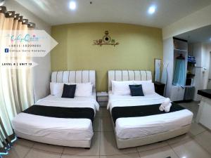 dwa łóżka siedzące obok siebie w pokoju w obiekcie Cahaya Qaira Homestay @ D'Perdana Kota Bharu w mieście Kota Bharu