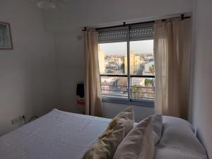 um quarto com uma cama e uma grande janela em Dto Tejedor em Mariano J. Haedo