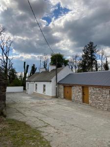 a white building with a garage in front of it at Toms Cottage in Longford