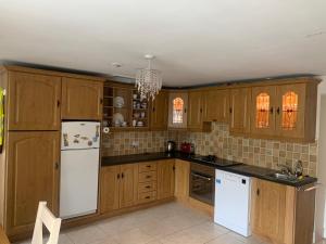 cocina con armarios de madera y nevera blanca en Toms Cottage en Longford