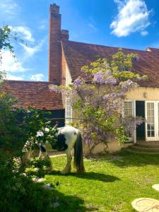 a horse standing in the grass in front of a house at Farmhouse Retreat with Hot Tub, Pool, Horses, Games Room, Free Car Park, Only 45 min from Oxford Circus in Stapleford Tawney